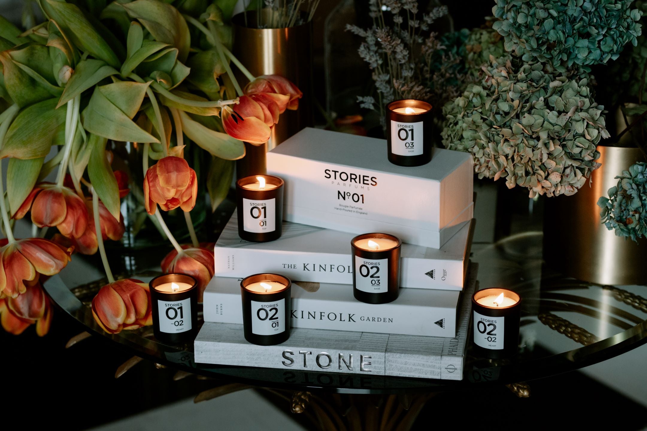 3 STORIES perfumed candles alight in black votives on marble plinth