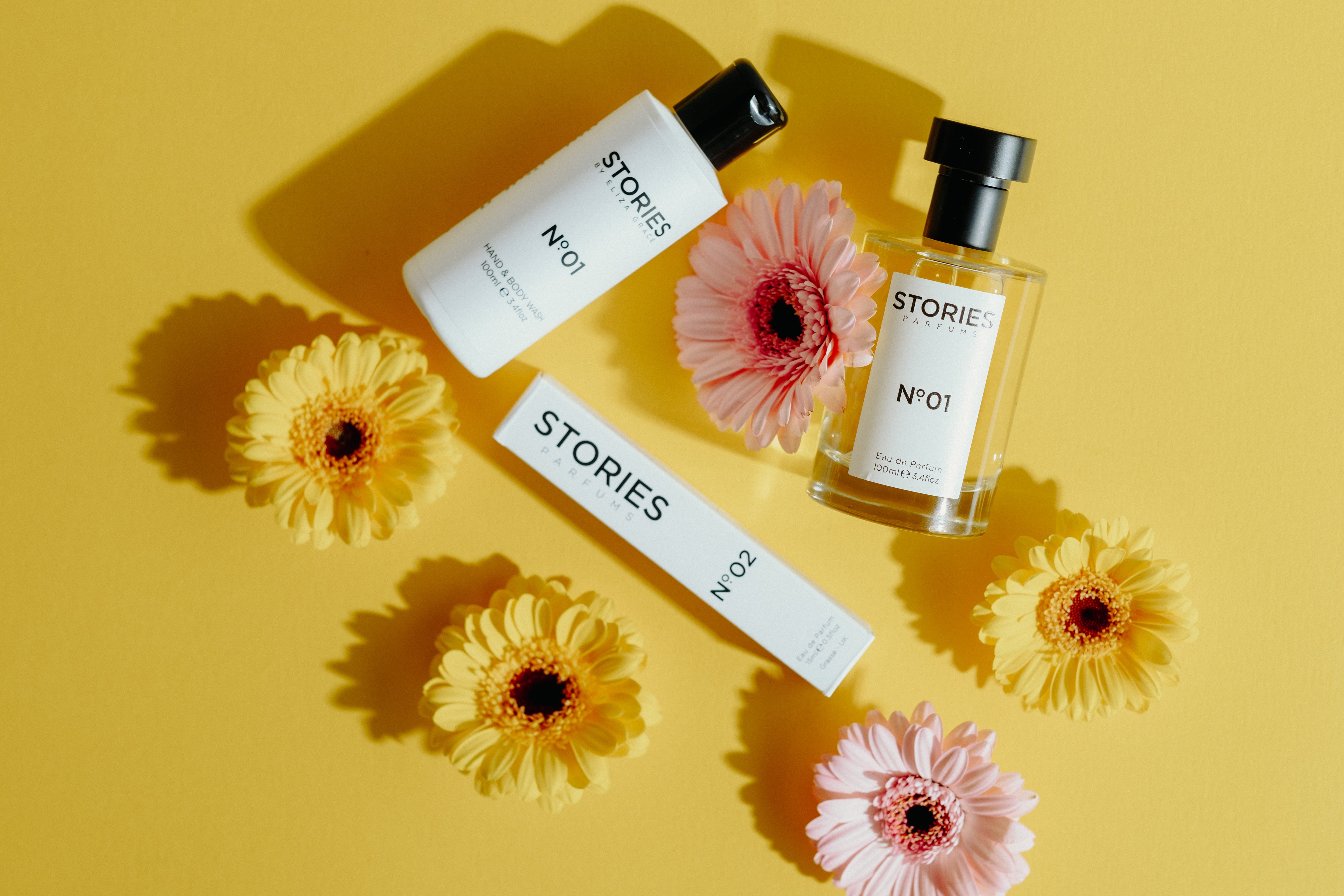 STORIES Parfums fragrance and body bottles on a yellow background with flowers