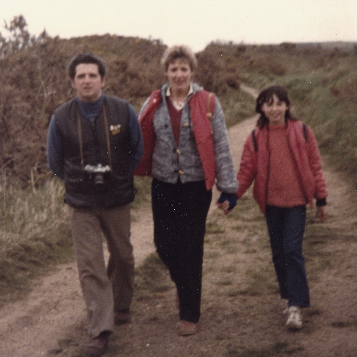 Tonya as a child, walking a coastal path hand in hand with her parents