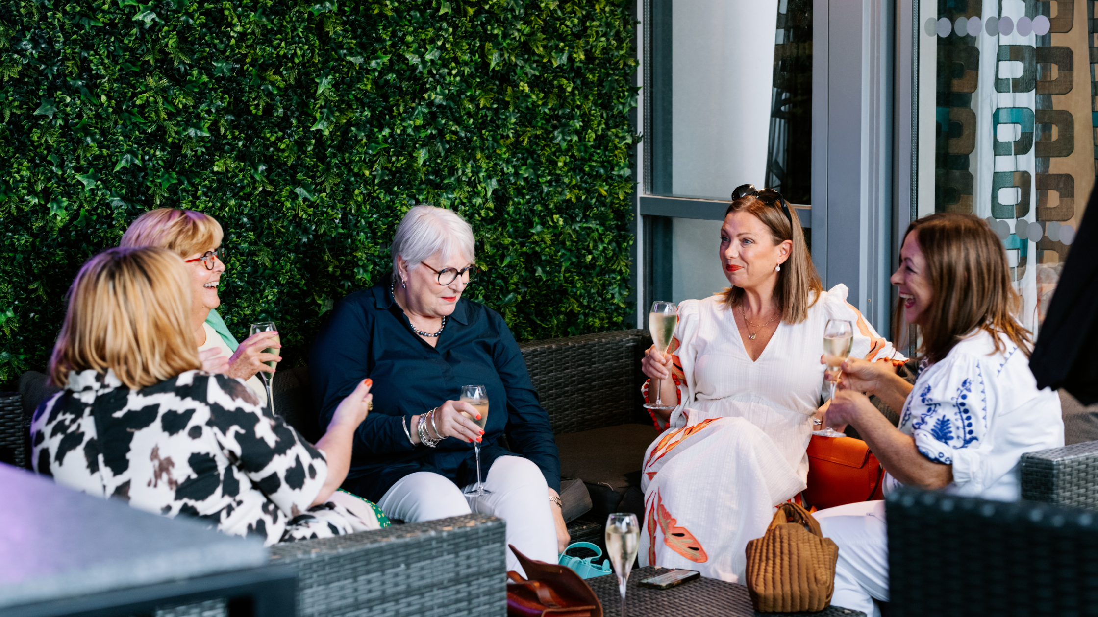 STORIES SCENT SOCIETY GATHERING, GUESTS SITTING IN GARDEN DRINKING CHAMPAGNE ON ARRIVAL