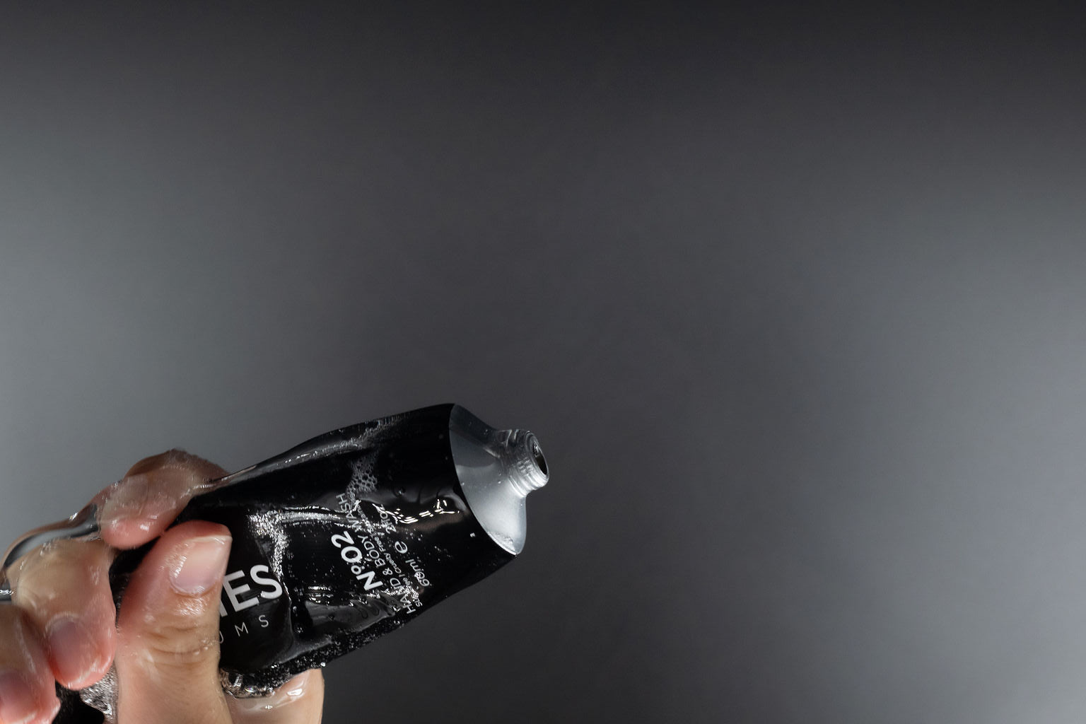 hand squeezing black tube of STORIES Hand and Body Wash