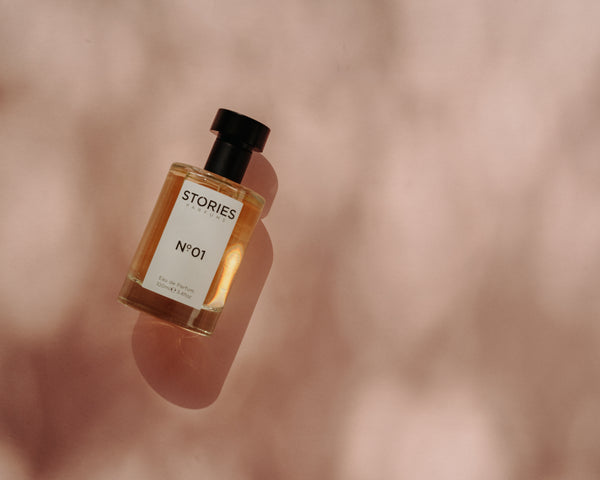 STORIES Parfums No.01 bottle laying on its side on dappled peachy background