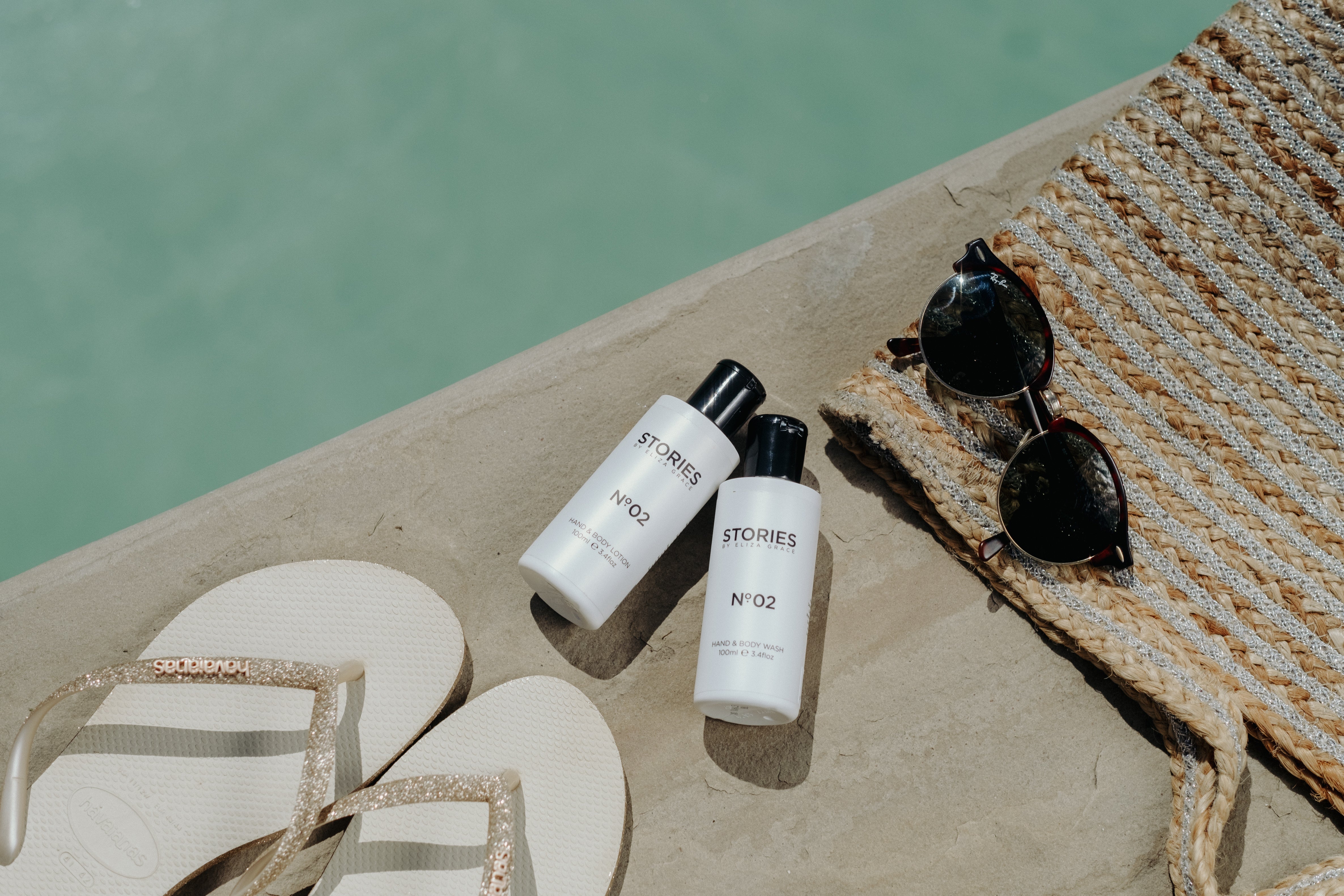STORIES Parfum Hand and Body Travel Duo by the pool with flipflops and sunglasses. 