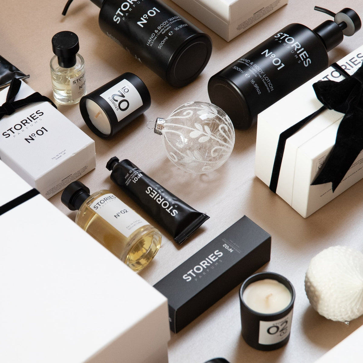 STORIES Nº.01 Christmas flat lay with Hand & Body Wash and Lotion, Eau de Parfum and a gift box tied with black velvet ribbon